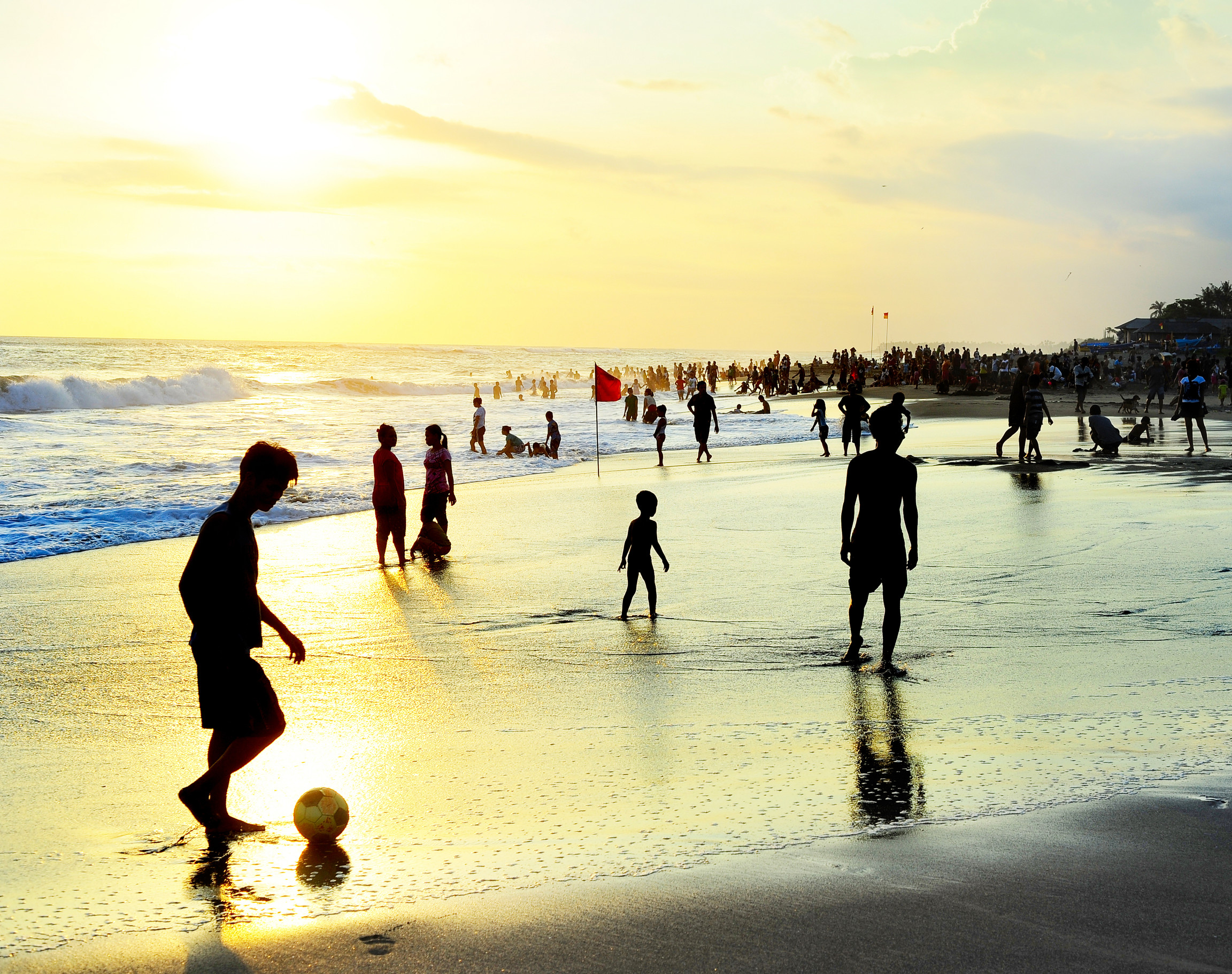 People playing football on the sandy beach