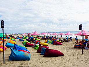 Colorful bean bags on sandy beach under cloudy sky