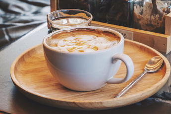 Latte served with cookie on a wooden tray