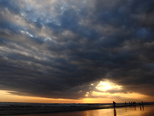 Cloudy beach sunset with people in silhouette