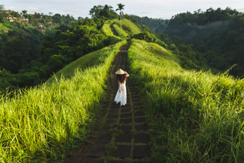Person walking along a green hilltop trail in Ubud