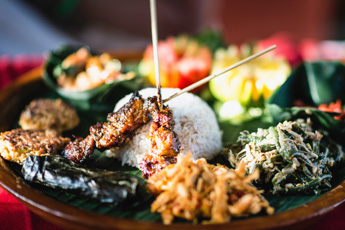 Plate of grilled skewers and vegetables on a red background