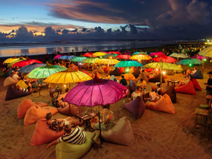 Crowded beach with colorful umbrellas at sunset