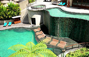 Resort with lush plants and a green-tiled infinity pool