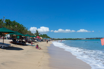 Quiet sandy beach with blue sky and calm waves