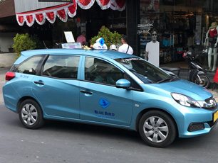 Blue taxi driving on city street