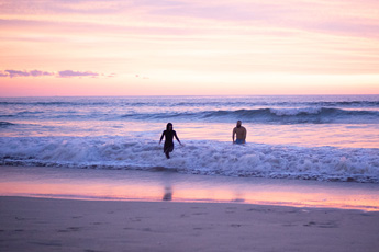 Couple walking into the ocean at sunset