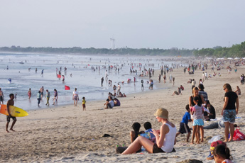 Busy beach scene with crowds and sun umbrellas