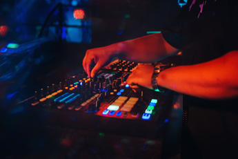 DJ mixing music with colorful lights in the background