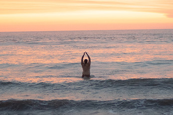 Person alone in the sea during golden hour