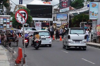 Busy road with cars, pedestrians, and scooters