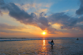 Silhouetted person walking into the sea during sunset